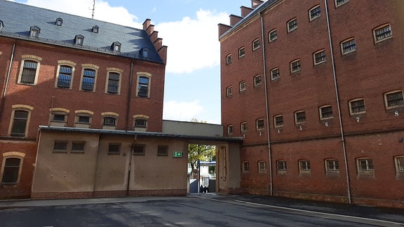 Blick vom Innenhof der Gedenkstätte Hoheneck auf rote Klinkerstein-Fassade und viele vergitterte Fenster. 