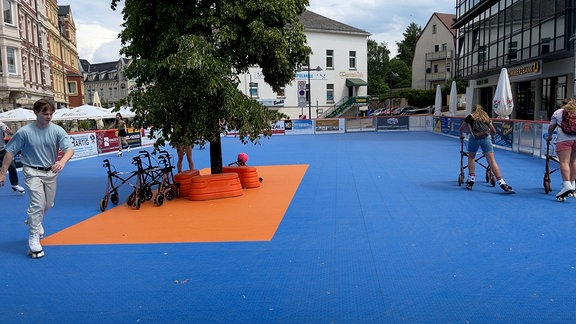 Eine glatte Fläche in Blau, Menschen fahren Rollschuh.