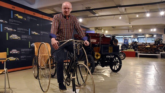 Sammler Albrecht Mugler sitzt auf einem historischen Dreirad.