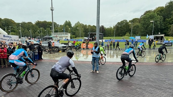 Radfahrende fahren in ein Stadion ein.