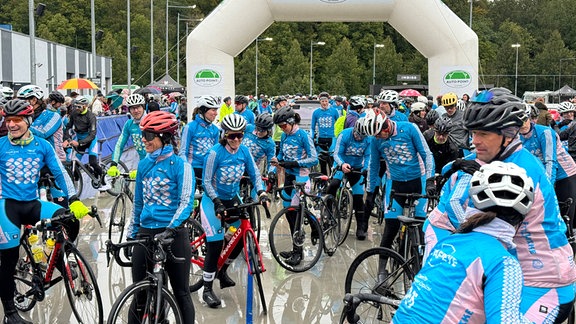 Eine Gruppe von Radrennfahrern steht auf Zieleinfahrt in einem Stadion.