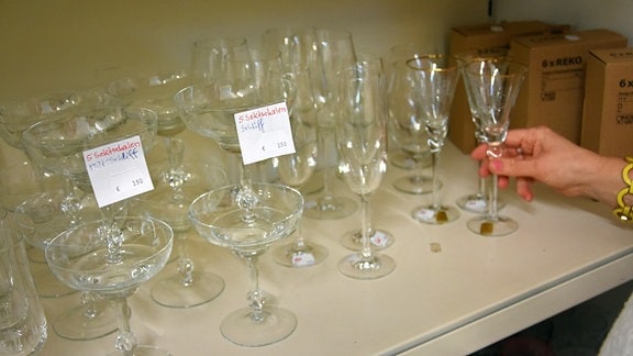 Eine Frau räumt verschiedene Gläser in ein Regal, die mit handgeschiebenen Preisschildern versehen sind. 