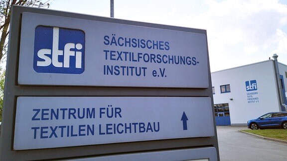 Auf einem Eingangsschild ist "STFI - Sächsisches Textilforschungsinstitut" zu lesen.