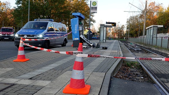 Ein Polizeiwagen steht an einer abgesperrten Haltestelle mit einem zerstörten Ticketautomaten.