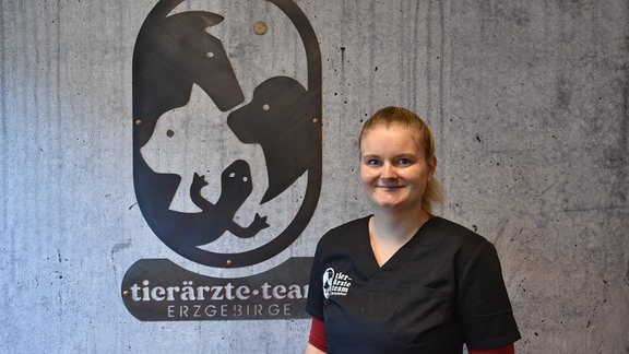 Julia Hübner, Tierärztin aus Zwönitz, vor einer Wand mit Logo "Tierärzteteam".