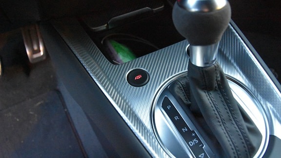 Ein Schalter in der Mittelkonsole eines Sportwagens mit einem Auspuffsymbol