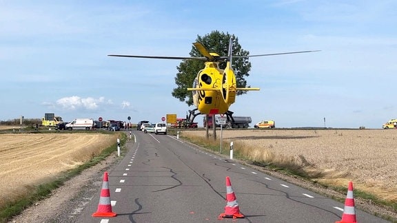 Ein gelber Hubschrauber startet auf einer Straße vor einer Kreuzung