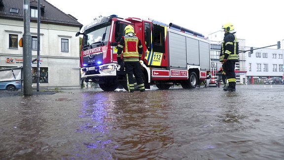 Feuerwehrleute in überfluteter Straße