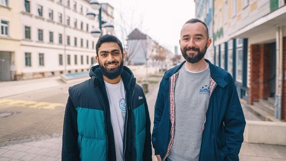 Muhammad Ahmad Afghan und Thomas Höppner stehen nebeneinander in einer Fußgängerzone.