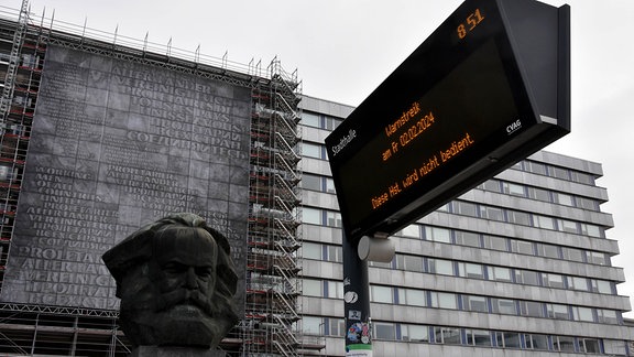 Ein Haltestellenschild mit Streikhinweis vor dem Karl-Marx-Monment in Chemnitz.
