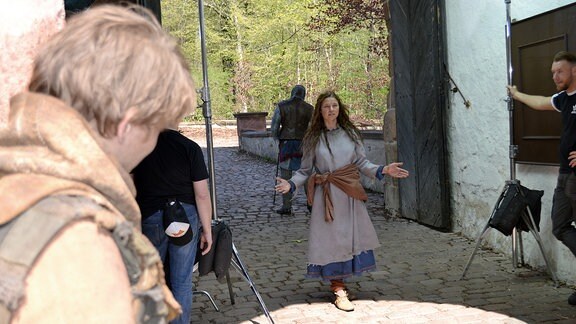 Eine als Bauernmädchen verkleidete Schauspielerin tritt durch das Tor von Burg Kriebstein.