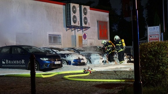 Feuerwehrleute löschen drei abgebrannte Autos.