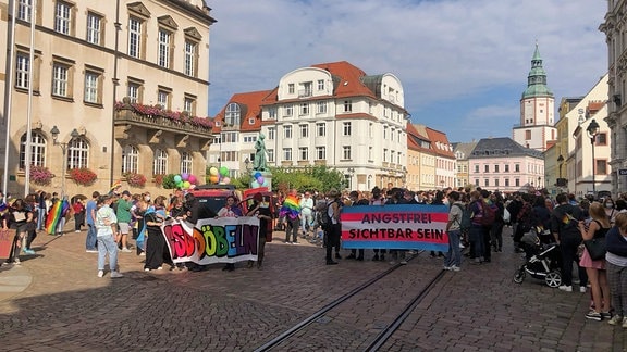 Vor dem Döbelner Rathaus stehen mehrere hundert bunt gekleidete Menschen mit Bannern "Angstfrei sichtbar sein", "CSD Döbeln".