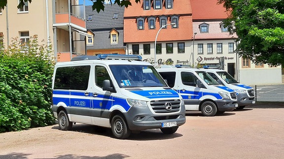 Auf einem Parkplatz in Döbeln stehen drei Polizeifahrzeuge nebeneinander.