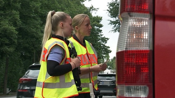 Zwei Polizistinnen kontrollieren ein Auto.