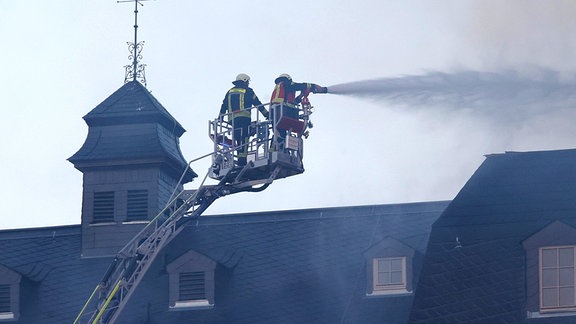Zwei Feuerwehrleute löschen einen Brand