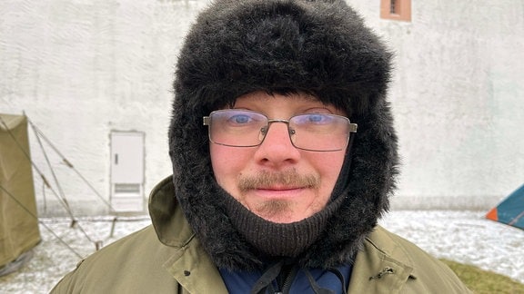 Ein Mann mit Bart, Brille und Wollmütze schaut in die Kamera