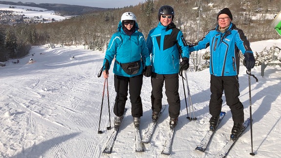 Drei Skifahrer im Schnee posieren für die Kamera.