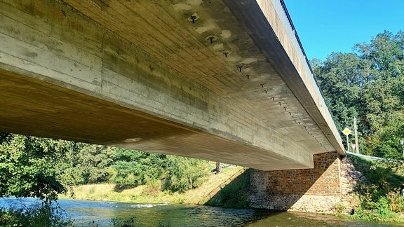 Eine Betonbrücke führt über einen Bach.