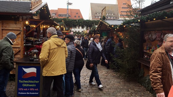 Menschen inmitten geschmückter Weihnachts-Verkaufsstände.