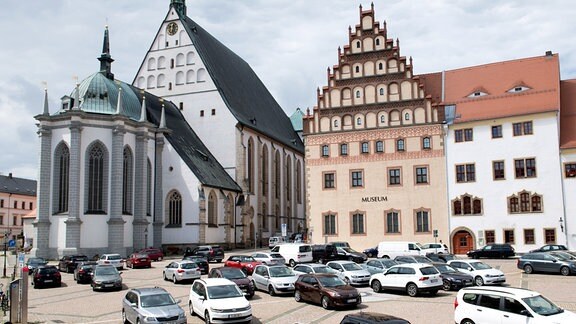 Autos stehen vor dem Stadt- und Bergbaumuseum (r) sowie dem Dom zu Freiberg.