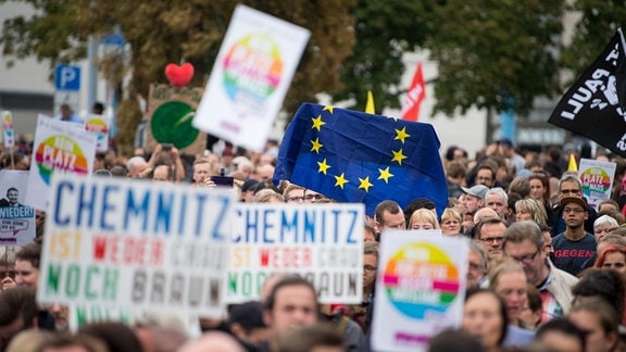Teilnehmer der Kundgebung des Bündnisses Chemnitz Nazifrei unter dem Motto «Herz statt Hetze» halten Schilder und eine Flagge der EU hoch. 