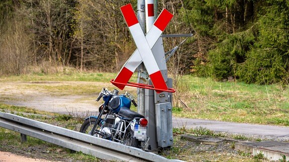 Ein Motorrad steht an einem Bahnübergang.