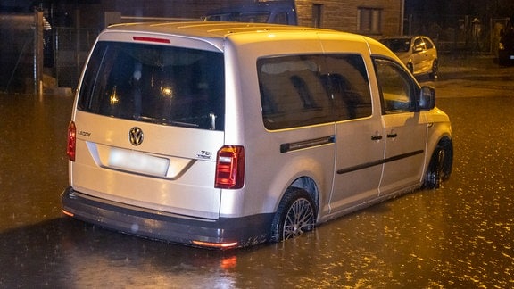 Ein Auto steht auf einer Straße tief im Wasser nach starken Regenfällen. 