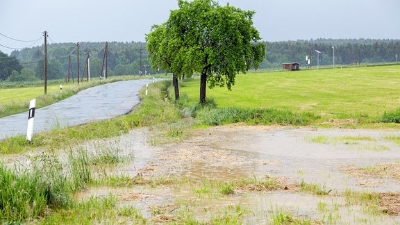 Landstraße und Feld von braunem Schlamm und Wasser bedeckt