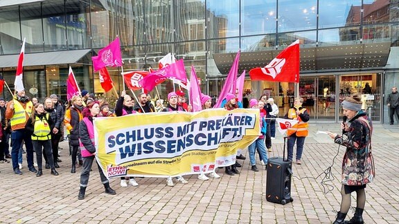 Eine Gruppe von Gewerkschaftern demonstriert auf dem Markt in Chemnitz. Eine Frau spricht ins Mikrofon.