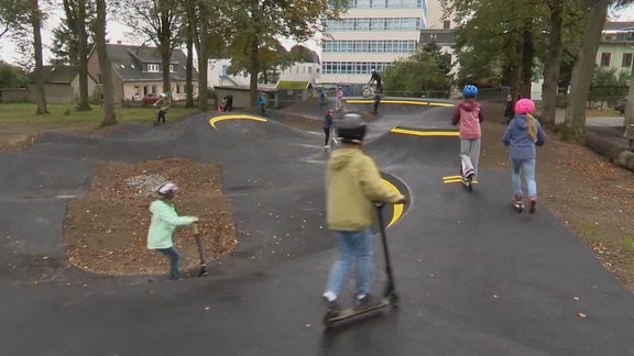 Kinder und Jugendliche auf Rollern und Fahrrädern auf der neugebauten Strecke.