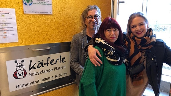 Gerald Kelpin, Cathrin Schauer-Kelpin und Eileen Schönheit vom Verein KARO stehen neben einer Babyklappe