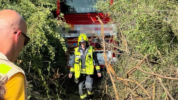 Ein Feuerwehrmann vor einem Bus in einem Gebüsch