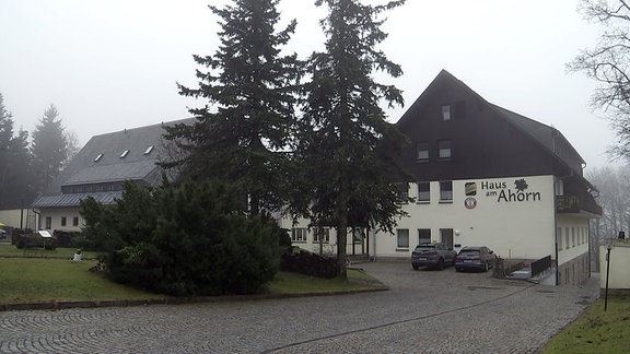 Das Hotel "Haus am Horn" im Nebel, davor Nadelbäume.