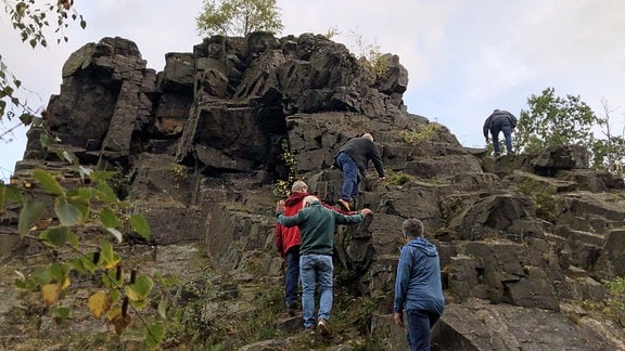 Männer steigen einen Felsen hinauf. 