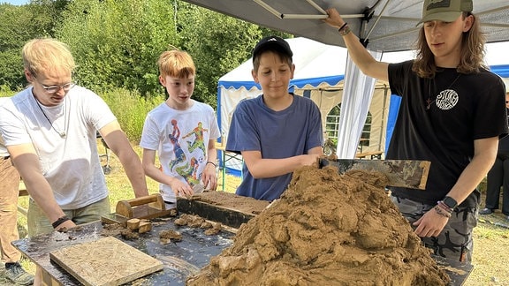 Kinder und Jugendliche stellen aus Lehm Ziegel her. 