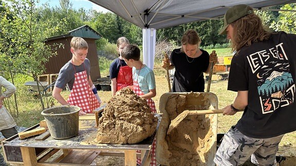 Kinder und Jugendliche stellen aus Lehm Ziegel her. 