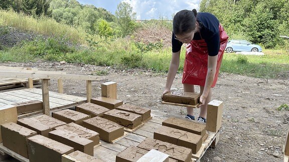 Kinder und Jugendliche stellen aus Lehm Ziegel her. 