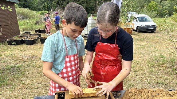 Kinder und Jugendliche stellen aus Lehm Ziegel her. 