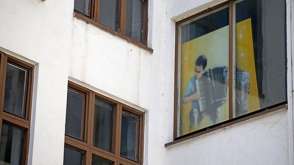 Das Bild eines Akkordeonspieler steht in einem Fenster