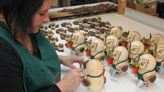 Mitarbeiterin Aline Schnalke fertigt Eulen aus Holz. 
