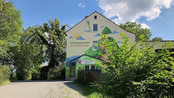 Ein Kindergarten mit einem großen bunten Wandbild. 
