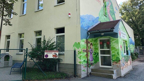 Ein Kindergarten mit einem großen bunten Wandbild. 