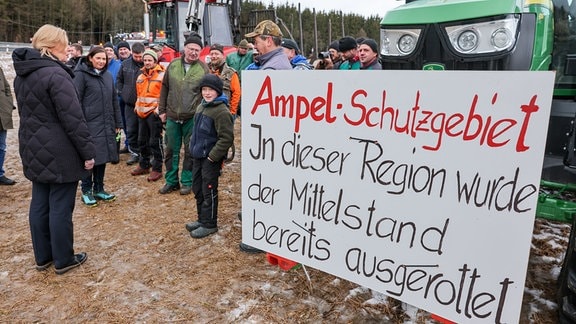 Forst- und Landwirte sprechen mit Bundestagspräsidentin Bärbel Bas (l, SPD), die bei einer Reise mit dem Bundestagspräsidium durch das Vogtland an einer Protestaktion von Bauern angehalten haben.