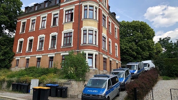 Vor einem sanierten Haus aus der Gründerzeit stehen drei Polizeiwagen in der Sonne. Sie gehören zum Polizeieinsatz, der Mitte Juni durchgeführt wurde.