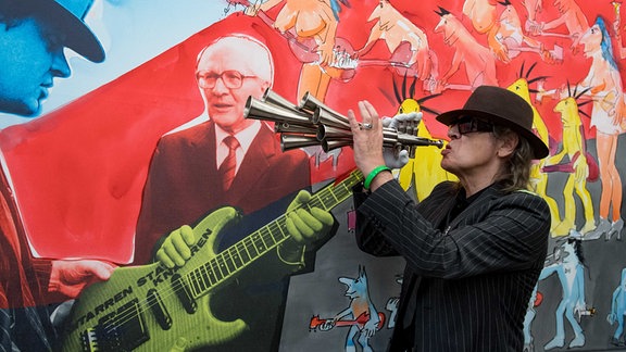 Der Musiker Udo Lindenberg spielt vor seiner Arbeit "Wer zu spät rockt... (Honey)", 2006 in seiner Ausstellung "Zwischentöne" im Museum der bildenden Künste in Leipzig auf der Schalmei, die ihm Erich Honecker einst schenkte.