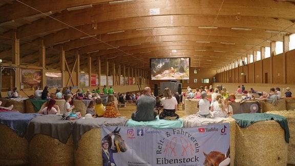 Menschen schauen sich einen Film im Wander- und Erlebniskino "Moviequidi" in Eibenstock an.