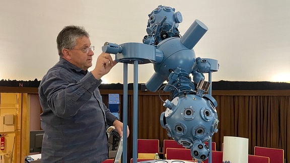 Ein Mann bedient einen Planetariums-Projektor.