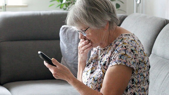 Seniorin telefoniert mit ihrend Händen und Fingern und ihrem Telefon.