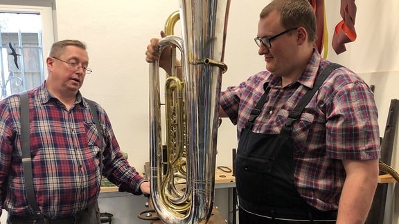Zwei Instrumentenbauer sin an einer Tuba zu Gange